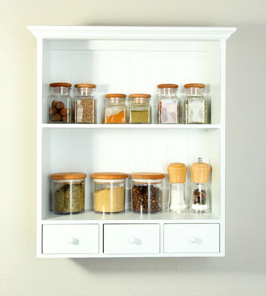 Hermosos estantes blancos con especias en botellas de vidrio —  Fotos de Stock