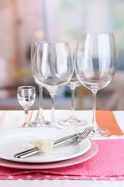 Table setting with glasses for different drinks on table on room background — Stock Photo, Image