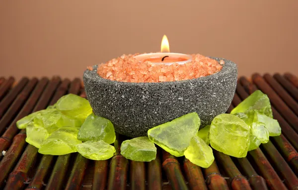 Candle in stone bowl with marine salt, on bamboo mat, on brown background — Stock Photo, Image