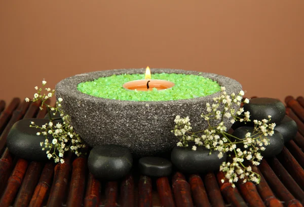 Candle in stone bowl with marine salt, on bamboo mat, on brown background — Stock Photo, Image