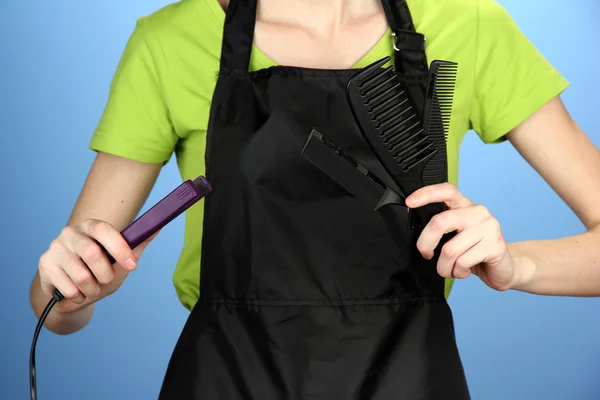 Cabeleireiro em uniforme com ferramentas de trabalho, em fundo de cor — Fotografia de Stock