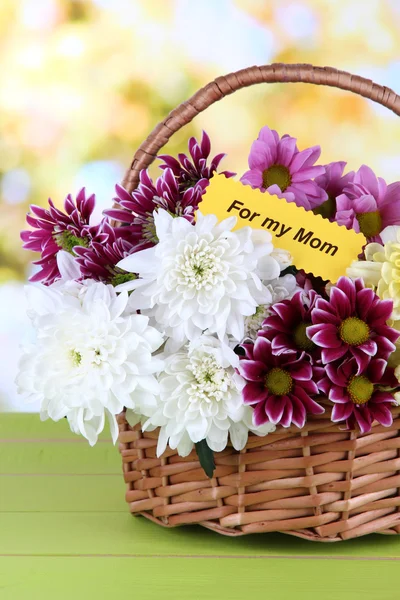Strauß schöner Chrysanthemen im Weidenkorb auf dem Tisch auf hellem Hintergrund — Stockfoto