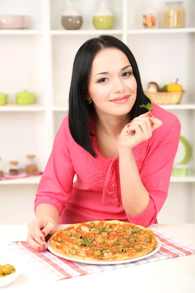 Mooi meisje met heerlijke pizza op keuken achtergrond — Stockfoto