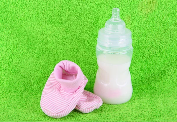 Flaska för mjölk och tossor på handduk bakgrund — Stockfoto