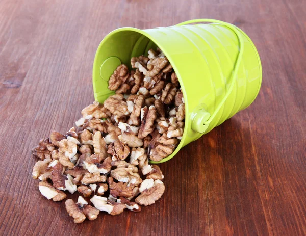 Overturned bucket with nuts on wooden background — Stock Photo, Image