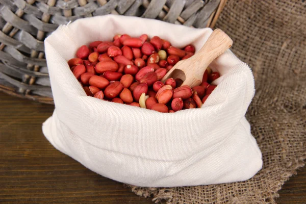 Peanuts in sack on wooden background — Stock Photo, Image