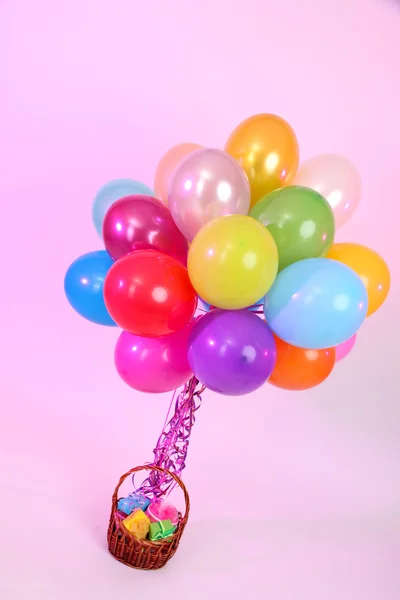 Много ярких воздушных шаров и корзины с подарками на фиолетовом фоне — стоковое фото