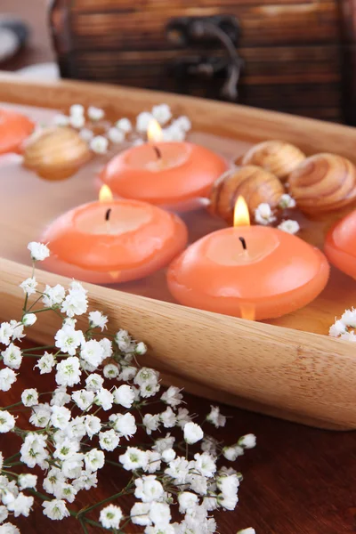 Beautiful candles in water on wooden table close-up — Stock Photo, Image