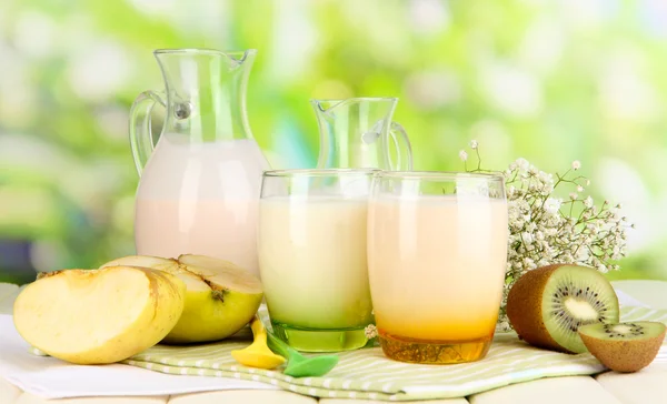 Heerlijke yoghurt met fruit in bril op houten tafel op natuurlijke achtergrond — Stockfoto