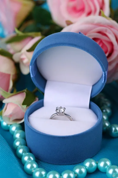 Rose and engagement ring on blue cloth — Stock Photo, Image