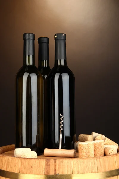 Вино и пробки на бочке на коричневом фоне — стоковое фото