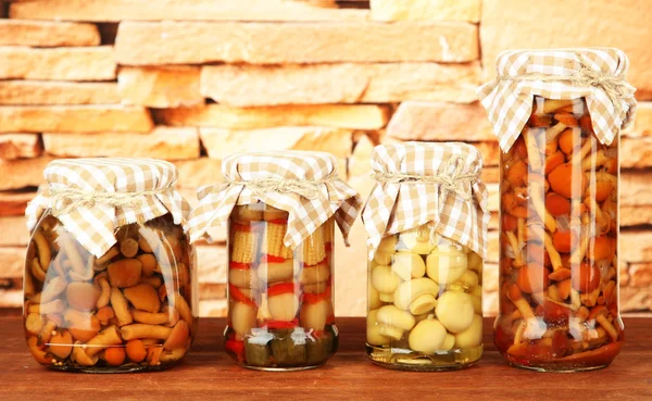 Deliciosos champiñones marinados en frascos de vidrio, sobre mesa de madera sobre fondo brillante —  Fotos de Stock