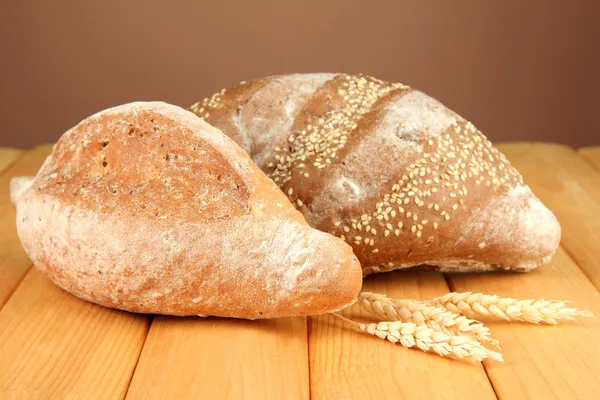 Composition with bread on wooden table, on color background — Stock Photo, Image