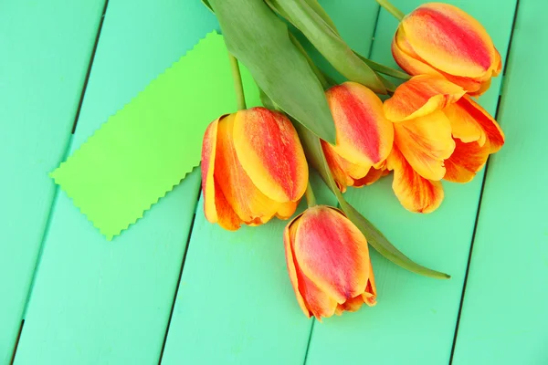 Krásné oranžové tulipány na barevné dřevěné pozadí — Stock fotografie