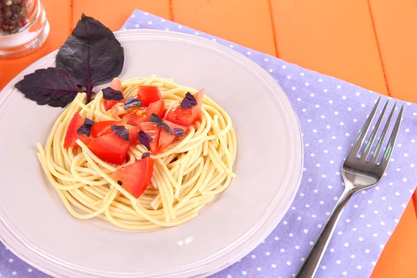 Spaghetti mit Tomaten und Basilikumblättern auf Serviette auf Holzgrund — Stockfoto