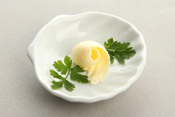 灰色の背景上の皿にバター カール — ストック写真