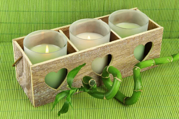 Candeliere in legno con candele e bambù, su tappetino verde — Foto Stock