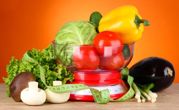 Fresh vegetables in scales on table on orange background — Stock Photo, Image