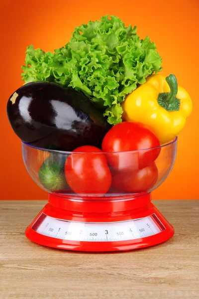 Fresh vegetables in scales on table on orange background — Stock Photo, Image