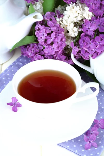 Composition with beautiful lilac flowers, tea service on wooden table, close up — Stock Photo, Image