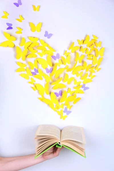 Paper yellow butterfly in form of heart fly out book — Stock Photo, Image