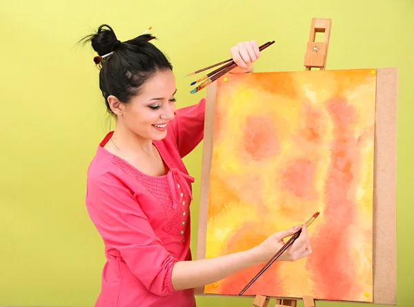 Beautiful young woman painter at work, on color background — Stock Photo, Image