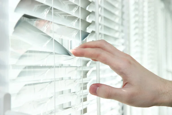 Someone looking out of window opening blinds — Stock Photo, Image