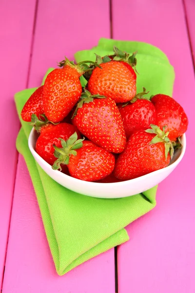 Verse aardbeien in kom op roze houten achtergrond — Stockfoto