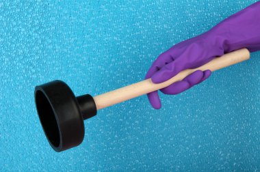 Toilet plunger in hand on blue background clipart