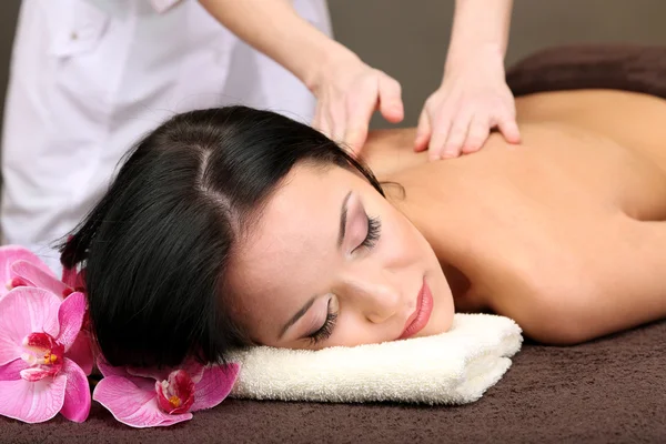 Bella giovane donna in salone spa ottenere massaggio con pietre spa, su sfondo scuro — Foto Stock