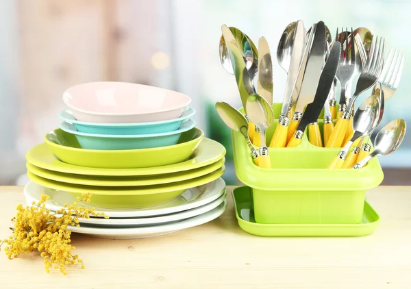 Placas, garfos, facas, colheres e outros utensílios de cozinha sobre fundo brilhante — Fotografia de Stock