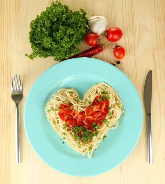 Gotowane spaghetti starannie ułożone w kształcie serca i polane sosem pomidorowym, na tle drewniane — Zdjęcie stockowe