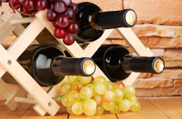 Botellas de vino colocadas sobre soporte de madera sobre fondo de pared de piedra — Foto de Stock