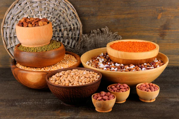 Different kinds of beans in bowls on wooden background — Stock Photo, Image