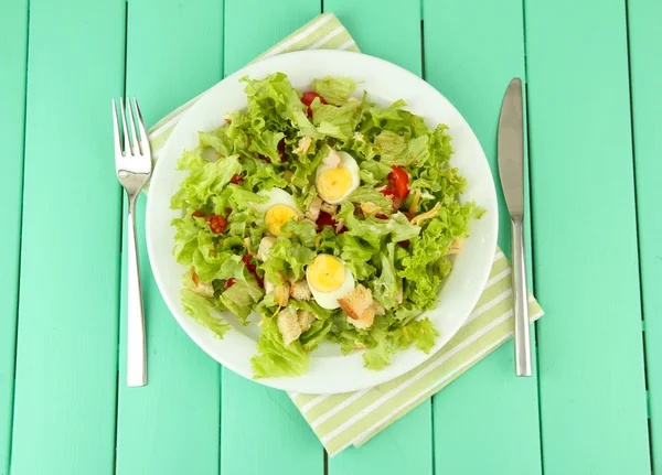 Cézár saláta fehér tányérra, színes fából készült háttér — Stock Fotó