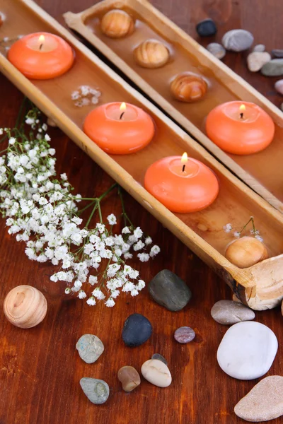 Schöne Kerzen im Wasser auf Holztisch in Großaufnahme — Stockfoto