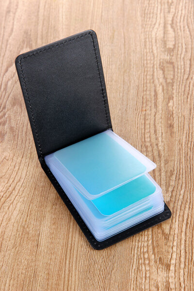 Держатель черной визитки на деревянном фоне
