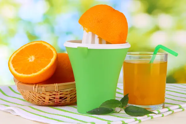 Citrus press, glass of juice and ripe oranges on white wooden table — Stock Photo, Image