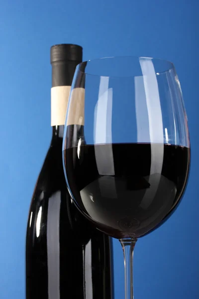 Wein im Glas und Weinflasche Nahaufnahme auf blauem Hintergrund — Stockfoto