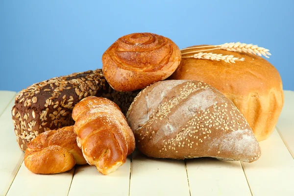 Composition with bread and rolls on wooden table, on color background — Stock Photo, Image