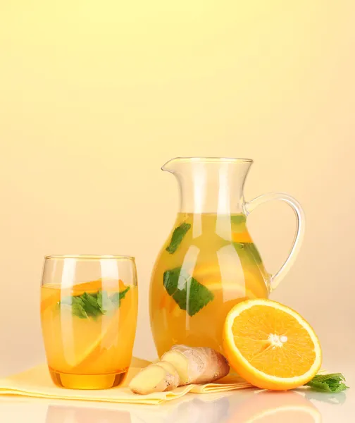 Apelsin saft i kanna och glas på gul bakgrund — Stockfoto