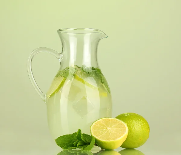 Lemonade in pitcher on green background — Stock Photo, Image