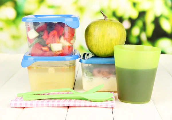 Leckeres Mittagessen in Kunststoffbehältern, auf Holztisch vor hellem Hintergrund — Stockfoto