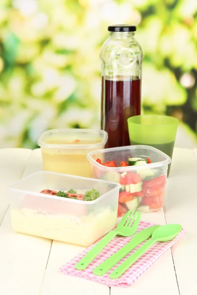 Chutný oběd v plastových nádobách, na dřevěný stůl na světlé pozadí — Stock fotografie