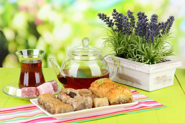Baklava doce na placa com chá na mesa no fundo brilhante — Fotografia de Stock