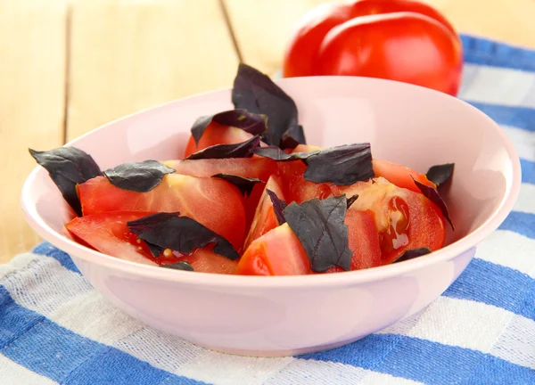 新鲜的西红柿与罗勒沙拉叶在一碗中对木制背景上餐巾 — 图库照片