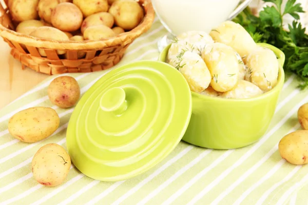 Tender young potatoes with sour cream and herbs in pan on wooden table close-up — Stock Photo, Image