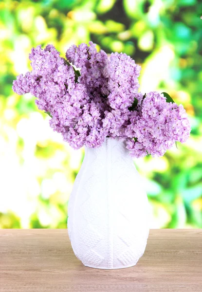 Piękne kwiaty bzu na stole na jasnym tle — Zdjęcie stockowe