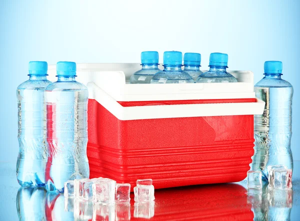Réfrigérateur ambulant avec bouteilles d'eau et glaçons, sur fond bleu — Photo