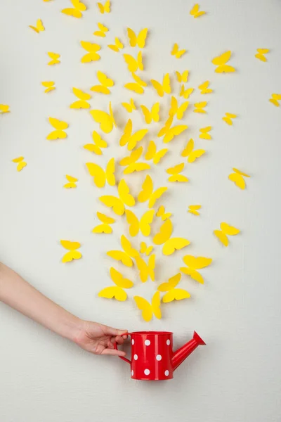 Žlutého papíru motýli létají z konev — Stock fotografie